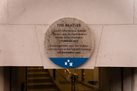 Round Dublin City Council plaque in Irish and English marking the Beatles' only two Dublin concerts at the Adelphi Cinema, 7 November 1963