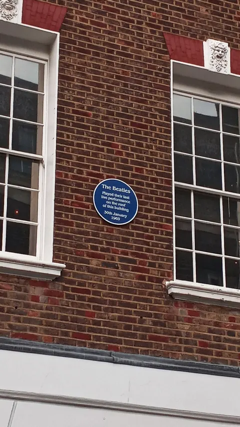 Round blue plaque on the brick front of 3 Savile Row, London, marking the Beatles' rooftop performance of 30 January 1969