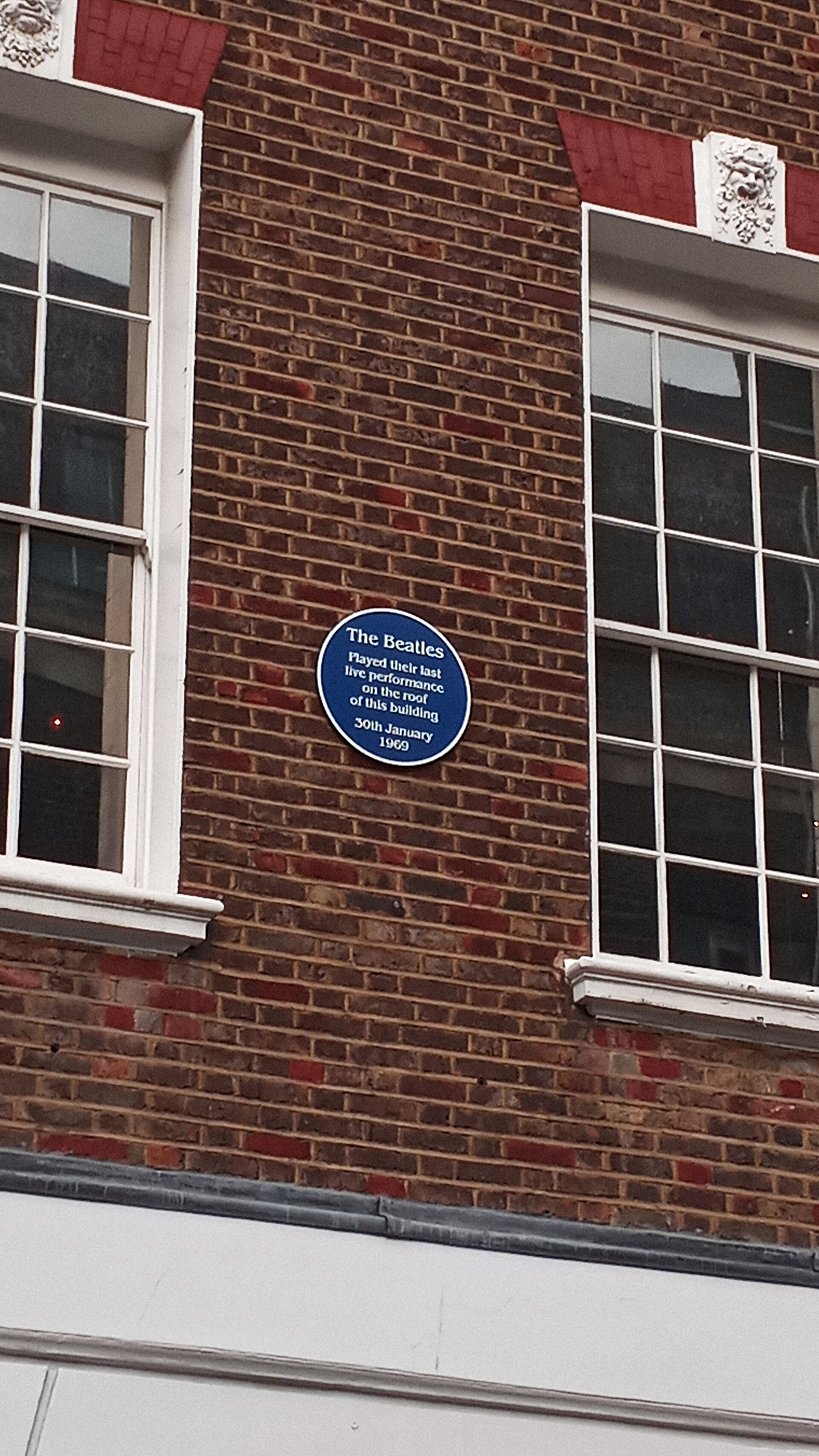 Round blue plaque on the brick front of 3 Savile Row, London, marking the Beatles' rooftop performance of 30 January 1969