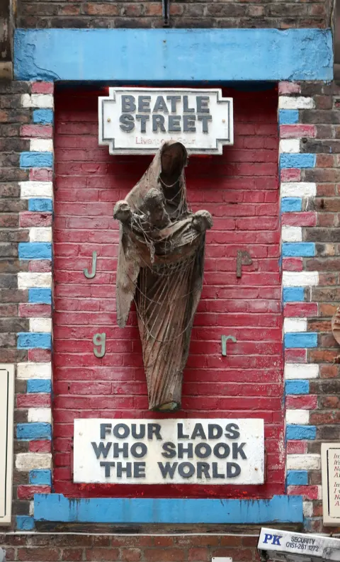 Arthur Dooley's Four Lads Who Shook the World sculpture, a Madonna figure holding infant Beatles, on the wall of Eric's on Mathew Street, Liverpool