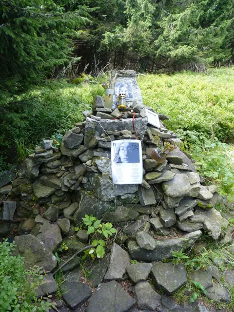 Stone cairn of the John Lennon memorial below the summit of Smrk in the Beskydy mountains, with photos of Lennon and candles on top