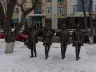 Four life-size standing Beatles figures in long coats on a snowy pavement on the Arbat pedestrian zone in Astana, February 2019