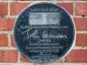 Round black plaque to Julia Lennon and John Lennon on the brick wall of the former Liverpool Maternity Hospital, Liverpool