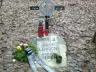 John Lennon memorial in the woods at Česká Skalice: a metal cross with a peace sign and a stone inscribed JOHN LENNON, with candles and a wreath